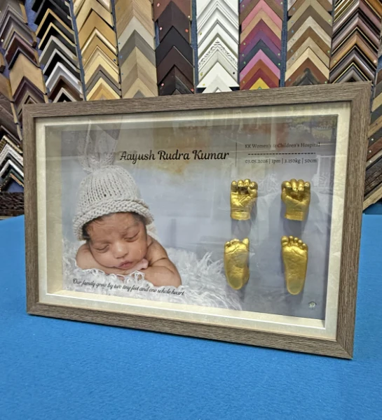 Baby keepsake shadow box framing with hand casts, foot casts, photograph, and birth details.