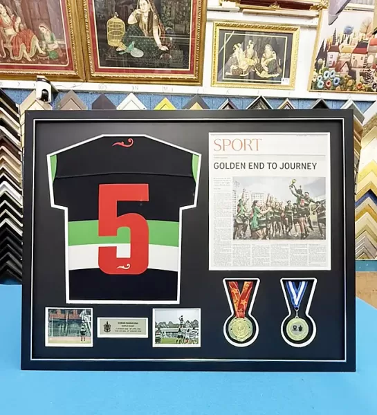Sports jersey framed with medals, newspaper article, and memorabilia in a custom shadow box frame.